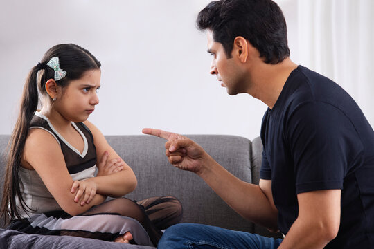 Father scolding her daughter by showing finger at home