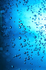 Clear water with bubbles on blue background, closeup