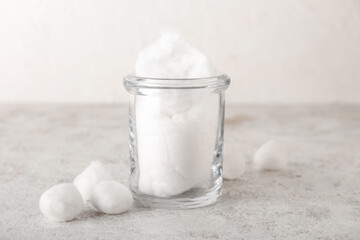 Glass jar with cotton wool on light background