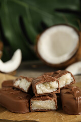 Delicious milk chocolate candy bars with coconut filling on table, closeup. Space for text
