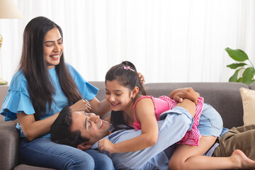 Little girl playing with her parent in living room 
