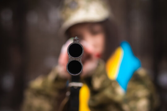 a young girl in military uniform holds a gun in her hands, on her shoulders the flag of Ukraine, aims and shoots, the army defends Ukraine, weapons machine gun, salutes in uniform 