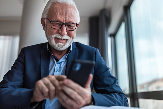 Senior businessman checking using mobile smart phone i modern office