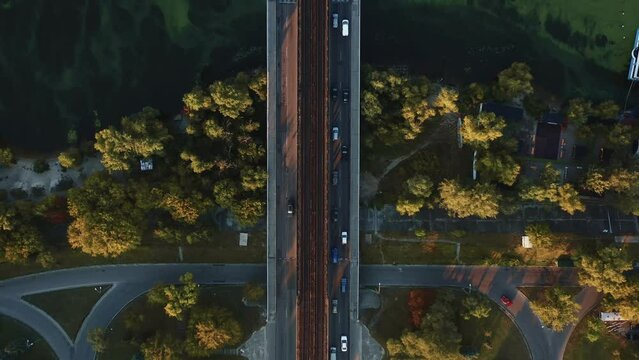 Top view cars and metro trains cross Dnepr river over one bridge, amazing aerial flyover shot of summer Kyiv, Ukraine.