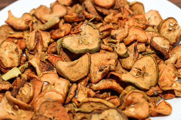Dried apple fruits on a plate on a wooden table.