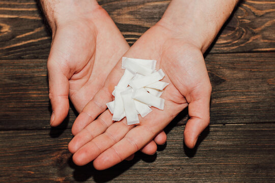 Palms with snus with nicotine pouches on a wooden background.