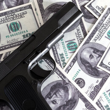 A square photo of a gun on a pile of hundred-dollar bills. Pistol tt on a pile of money.