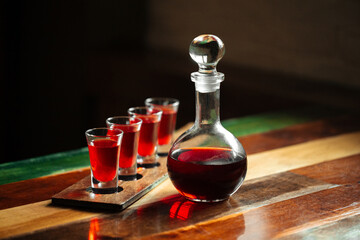 Decanter with red berry liqueur and shot glasses on the table