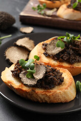 Delicious bruschettas with truffle sauce and microgreens on black table, closeup