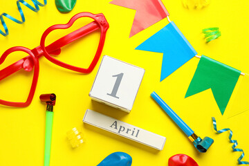 Calendar with date of April Fools Day and party decor on yellow background
