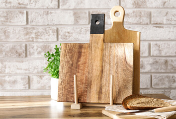Wooden cutting boards and bread on table near brick wall