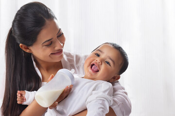 Mother feeding her little baby with bottle at home