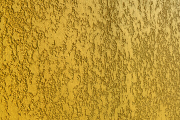 Close-up, texture of a yellow house facade wall made of decorative plaster.