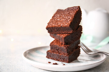 Plate with pieces of delicious chocolate brownie on light background