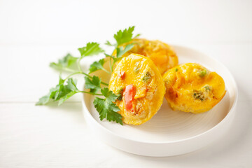 Egg muffins ( bites) and parsley leaves  in a plate on a gray background.