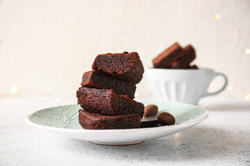 Plate with pieces of delicious chocolate brownie on light background