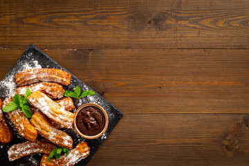 Plate with fried churros and chocolate sauce, top view