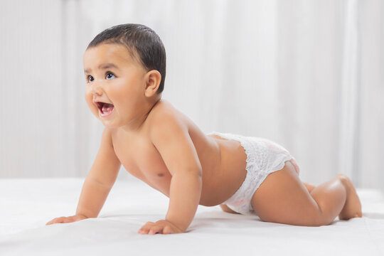 Cute Baby In Diaper Crawling On Bed