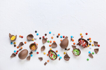 Fototapeta na wymiar Composition with tasty broken chocolate Easter eggs and candies on light background