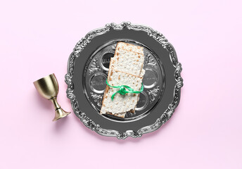 Passover Seder plate, flatbread matza and cup on pink background