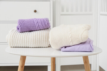 Stack of knitted sweaters on table in light room