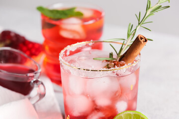 Glasses of tasty pomegranate cocktail on light background