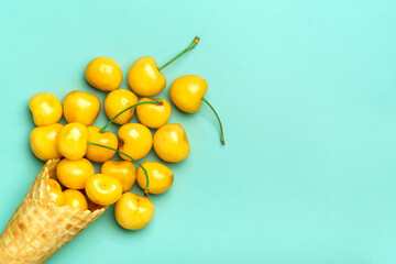 Fresh yellow cherries in waffle cones Ice cream cone filled with fresh sweet cherry on green background. Top view. Copy space. Summer creative concept Flat lay Healthy food