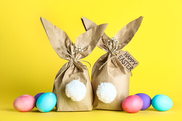 Paper bags bunny with Easter eggs on color background