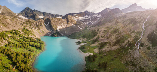 Naklejka na ściany i meble Panoramic aerial view of a natural wonder - turquoise and emerald lake in the middle of mountain peaks with glaciers. Pure and untouched nature