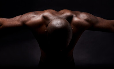 Fototapeta na wymiar Pure muscles and masculinity. Studio shot of a muscular african american man leaning forward.