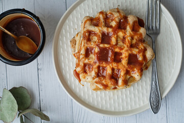Poppy seed waffles with caramel sauce. Wooden background. Top view. 