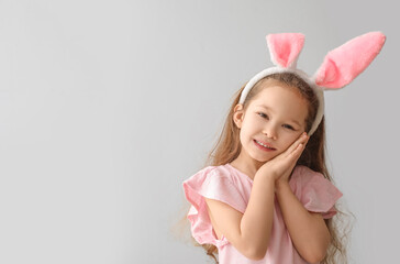 Cute little girl with bunny ears on grey background