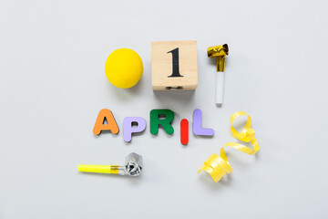 Composition with date 1 APRIL and party decor on light background. April Fools Day celebration
