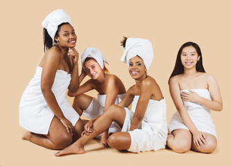 Multiethnic women with diverse skin and body types laughing together while using spa body towels...