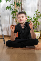 little kid boy practicing yoga, sitting in lotus position, indoor full length. Yogi kid on meditation and breathing session. Self isolation, keep calm. Kids sport home quarantine. Pranayama. Child hea