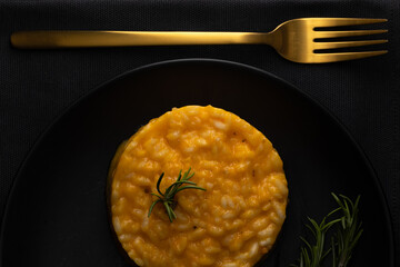 Milanese risotto on a black plate.