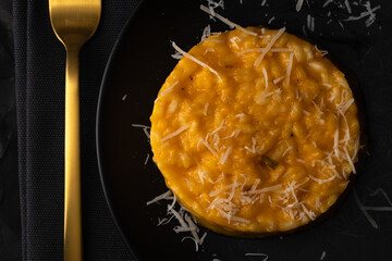 Milanese risotto on a black plate.
