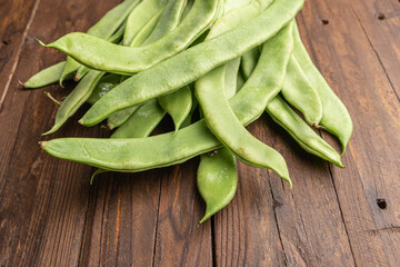 Raw green beans closeup. Fresh green bean also known as french beans, string beans, snap bean, snaps and haricots vert on wooden