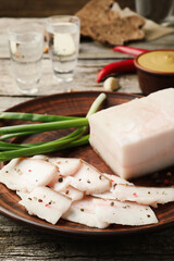 Tasty salt pork with green onion served on wooden table, closeup