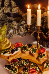christmas dinner with candles. Italian bruschetta with cream cheese, strawberry, arugula and balsamic vinegar sauce with honey