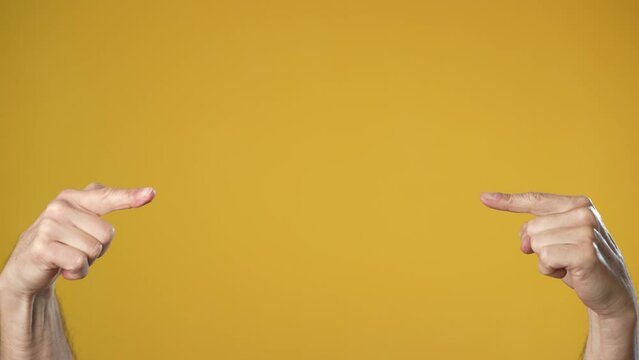 Two male hands pointing on copy space text place gesture isolated on yellow background studio. Copy space commercial promo advertisement. Advertising workspace mock up