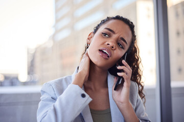 A young business woman rubs her neck while on a call in the city office