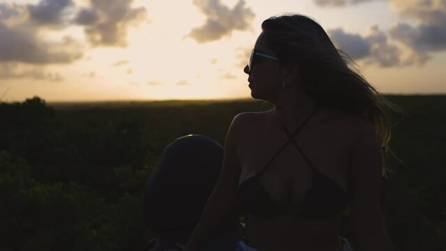 Latin woman watching the sunset in the dunes.