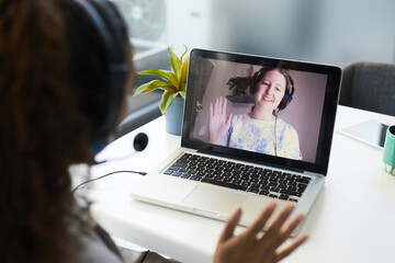 A screen showing a virtual meeting where a woman waves to her colleague