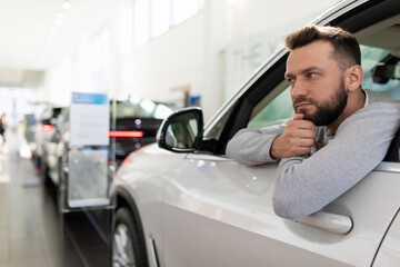 Buyer Sitting in a new car at a car dealership thinks about buying a car on credit