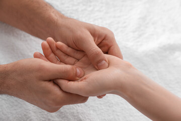 Woman receiving hand massage on soft towel, closeup