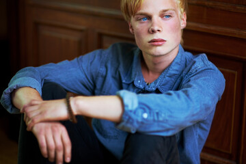 Brooding youth. Thoughtful and handsome young blonde guy with very blue eyes.