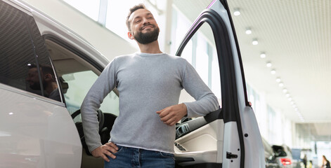 a man in a car dealership purchases a new car happy with a smile on his face