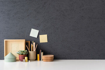Creative desk with notebook, desk objects, office supplies, books, and dark background. Organized...