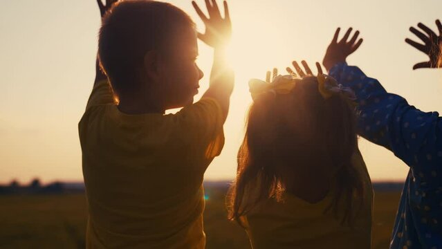 happy family kids people group pull hands to the sun teamwork. silhouette people party dancing recreation holiday. kids at a music concert pull their hands up. religion concept lifestyle sunlight